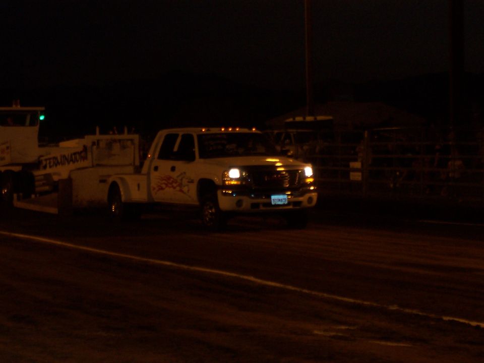 White pickup truck towing a trailer at night. Decals on the truck