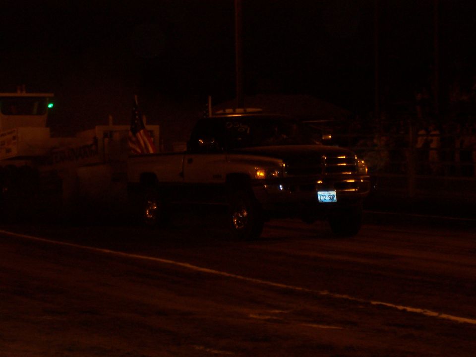 Dodge Ram pickup truck with an American flag on the bed, pulling a trailer at night