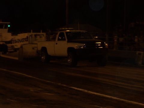 1994 Ford F-150 - A white and black pickup truck is seen with a trailer in the background at night.