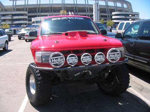1986 Ford Bronco - This modified SUV is parked in a lot with a stadium in the background.