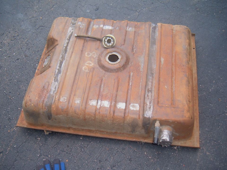 Rusty automotive steel fuel tank lying upside down on pavement