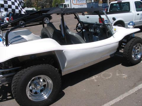 1986 Ford Bronco - A white dune buggy is parked in a lot with other vehicles and a checkered flag waving.
