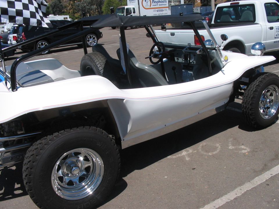 White dune buggy with black soft top, chrome wheels, and checkered flag