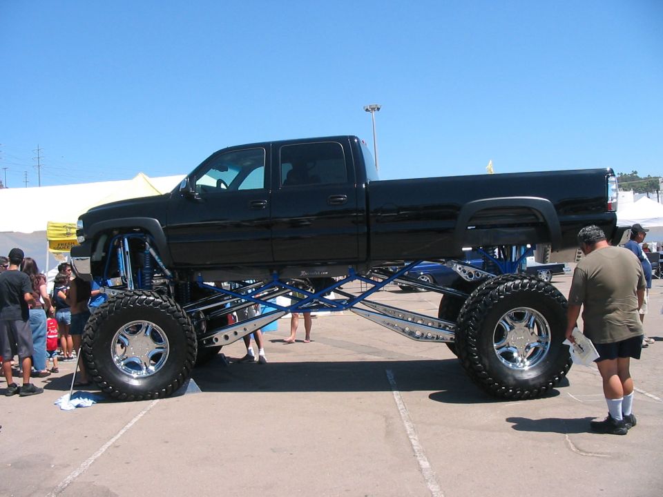 Black lifted pickup truck with custom blue suspension and large chrome wheels