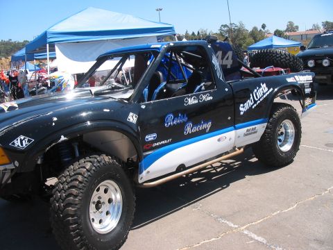 1986 Ford Bronco - A modified truck with racing livery is parked outdoors under a tent.