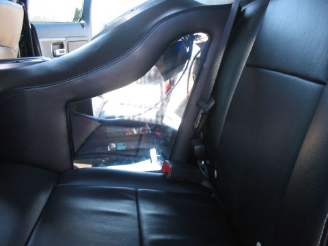 1986 Ford Bronco - Interior view of black leather seats and a roll bar, with a glimpse of the outside.