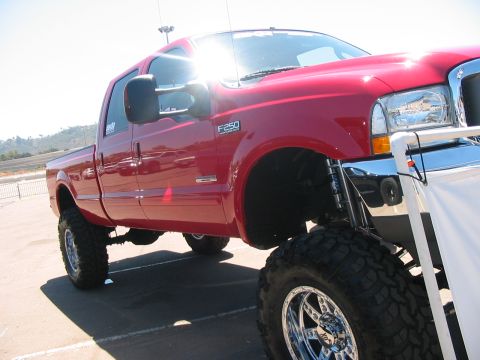 1986 Ford Bronco - This red Ford F-250 pickup truck features a lifted suspension and oversized tires.