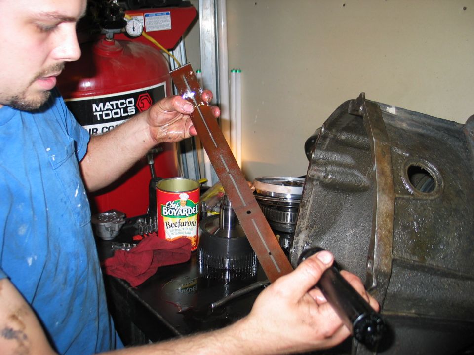 man holding transmission dipstick near transmission housing