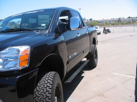 1986 Ford Bronco - A black pickup truck with V8 TITAN badging is parked outdoors, with a motorcycle visible in the background.