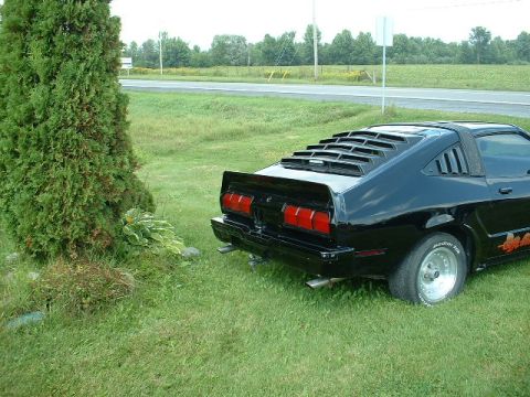 1978 Ford Mustang II - Rear view of a black coupe with distinctive louvers on the rear window and quarter windows.
