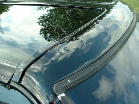 1978 Ford Mustang II - The reflection on the car's surface shows trees and a cloudy sky.