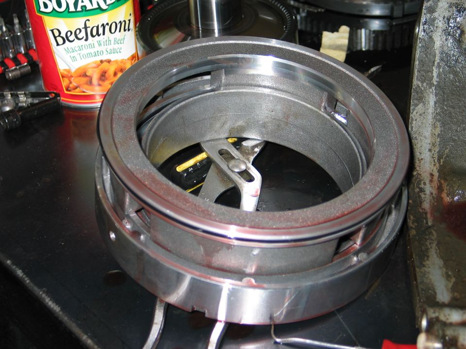 Metal transmission component with red fluid residue, next to a can of Beefaroni