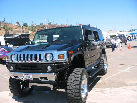 1986 Ford Bronco - A modified black Hummer H2 is parked outdoors under a clear blue sky.