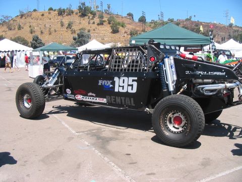 1986 Ford Bronco - A custom-built off-road buggy is parked outdoors with tents and spectators in the background.