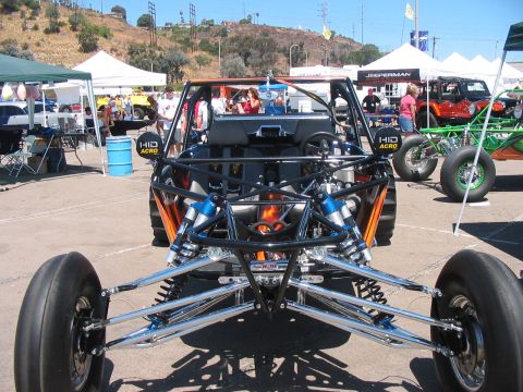 1986 Ford Bronco - A custom dune buggy is displayed at a car show, with other vehicles and tents visible in the background.
