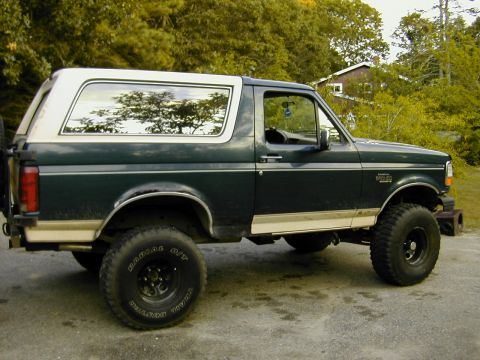1993 Ford Bronco - A lifted 1993 Ford Bronco with off-road tires is parked outdoors.