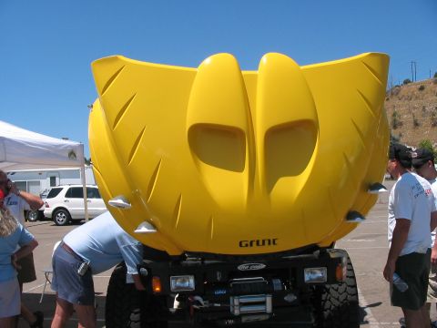 1986 Ford Bronco - A bright yellow custom hood with prominent scoops and 'GRUNT' lettering is displayed, with people and another vehicle in the background.