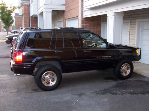 1996 Jeep Grand Cherokee - This Jeep Grand Cherokee has gold rims and appears to be lifted, parked in front of an apartment complex.