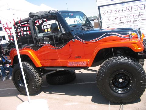 1986 Ford Bronco - This modified Jeep Wrangler features a striking orange and black paint scheme with flame graphics and aggressive off-road tires.