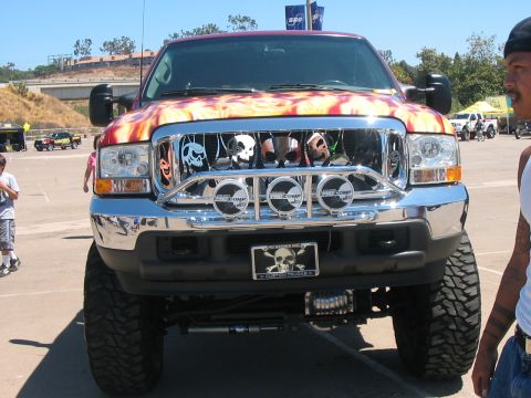 1986 Ford Bronco - This Ford F-Series truck features a custom grille with skull decorations and flame graphics on the hood.