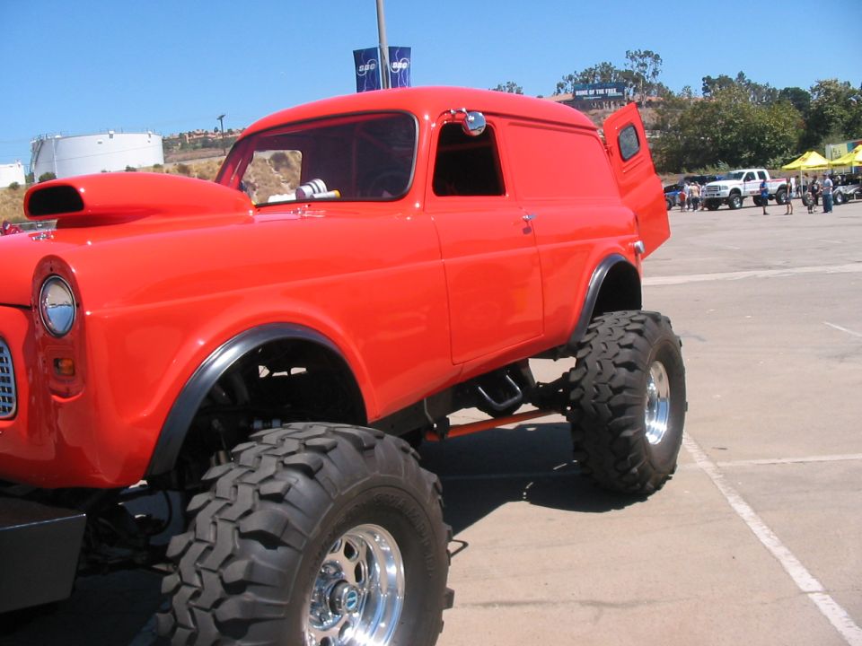red panel van with scoop on hood and huge off-road tires, door open