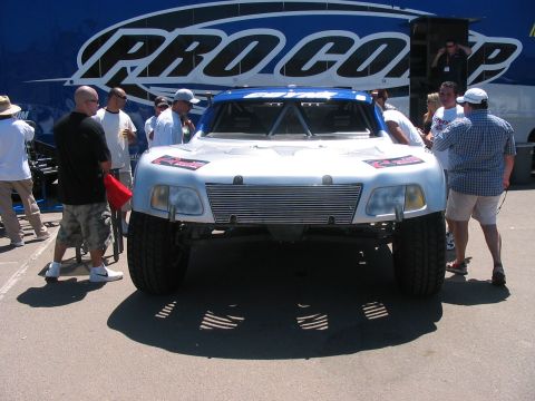 1986 Ford Bronco - A custom off-road truck is viewed from the front, with spectators gathered around.