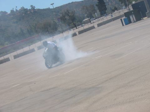 1986 Ford Bronco - A motorcycle is performing a burnout, creating a large cloud of smoke on a sunny day.