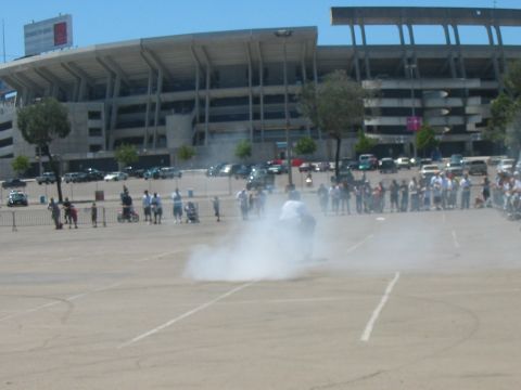 1986 Ford Bronco - A motorcycle creates a large cloud of smoke during a stunt performance in a stadium parking lot.