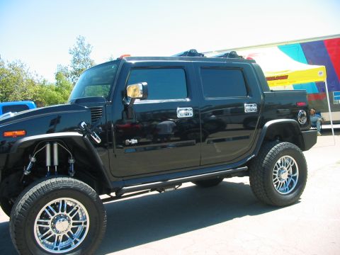 1986 Ford Bronco - A black SUV with custom wheels and suspension is parked outdoors.