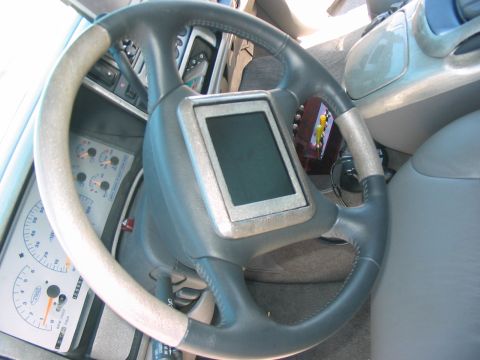1986 Ford Bronco - The interior of a vehicle is shown, focusing on the steering wheel and dashboard with a digital display and gauges.