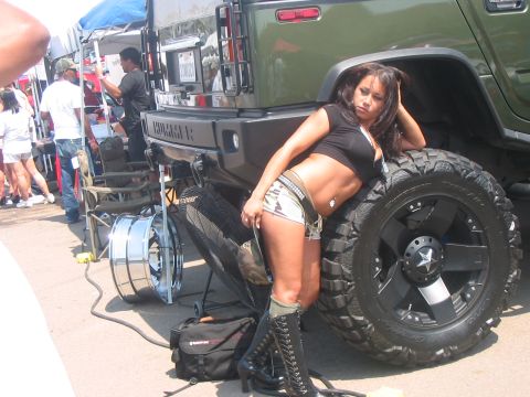 1986 Ford Bronco - A woman poses next to a green Hummer H2 SUV at an outdoor event.