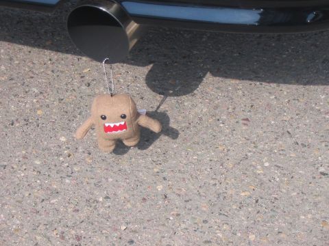 1986 Ford Bronco - Domo-kun keychain hangs from a vehicle's exhaust pipe.