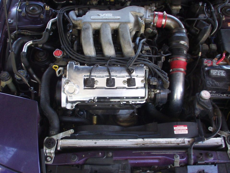 Engine bay with Mazda V6 DOHC 24-valve engine, chrome valve cover and red intake coupler