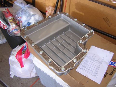 1984 Ford Bronco - A new transmission pan sits on a cardboard box, surrounded by household items.
