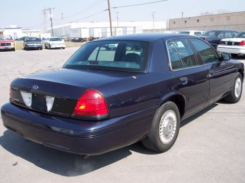 2000 Ford Crown Victoria - A dark blue 2000 Ford Crown Victoria is parked in a lot with other vehicles.