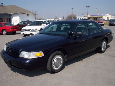 2000 Ford Crown Victoria - Dark blue 2000 Ford Crown Victoria parked in a lot with other vehicles visible.
