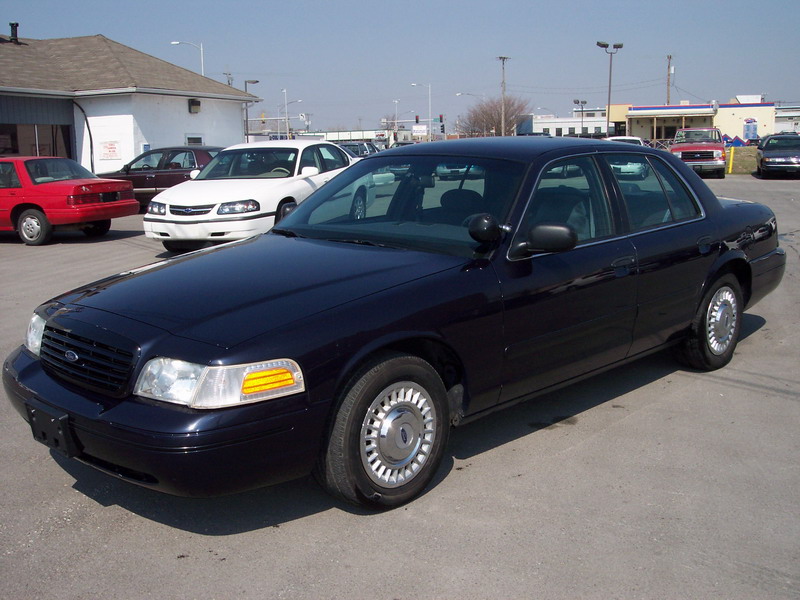 Dark navy Ford Crown Victoria police-package sedan parked on a lot, front three-quarter