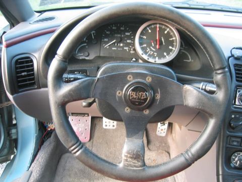 1993 Ford Probe - The interior of a 1993 Ford Probe shows an aftermarket steering wheel and a prominent tachometer gauge.