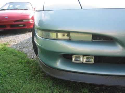 1993 Ford Probe - Front view of a teal 1993 Ford Probe, its bumper and fog lights, with another red car visible in the background.