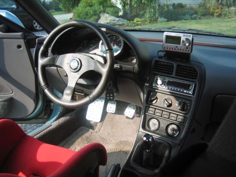 1993 Ford Probe - The interior of a car features a red racing seat, an aftermarket steering wheel, and a manual transmission shifter.
