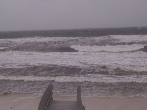 1995 Ford Bronco - Rough waves crash on the shore under a cloudy sky, viewed from a wooden walkway.
