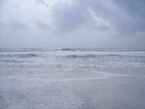 1995 Ford Bronco - The image depicts a stormy ocean scene with large waves rolling towards the shore under an overcast sky.