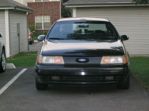 1990 Ford Taurus - Black 1990 Ford Taurus sedan parked in front of a garage.