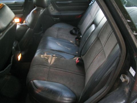 1990 Ford Taurus - The worn interior of a car, showing the rear seats and illuminated interior lights.
