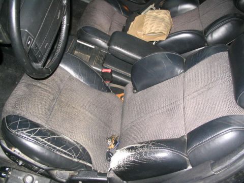 1990 Ford Taurus - The interior of a car shows cracked leather on the seats and a fabric center section.