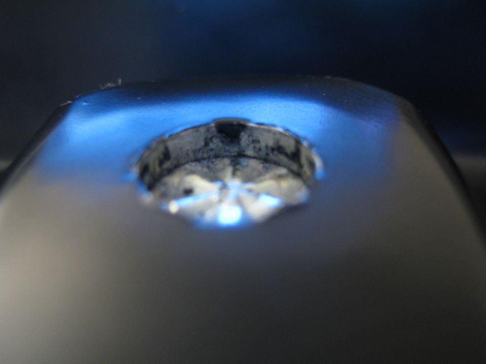Extreme close-up of a worn metal lock or ignition cylinder under blue lighting