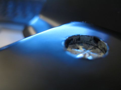 1990 Ford Bronco - macro close-up of a recessed circular lock cylinder set in a dark metal surface bathed in blue light.