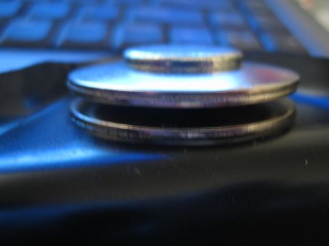 1990 Ford Bronco - close-up of stacked metal washers or thin discs resting on a glossy dark surface near a blue-illuminated keyboard.