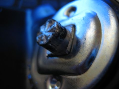 1990 Ford Bronco - macro shot of a worn splined metal shaft or key stub protruding from a metal lock body lit in blue.