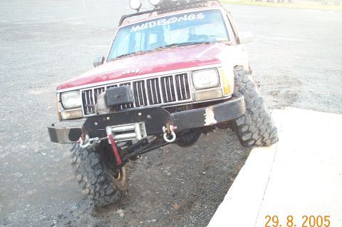 1988 Jeep Cherokee - This red Jeep Cherokee, modified for off-roading, is positioned at an angle on a concrete surface.